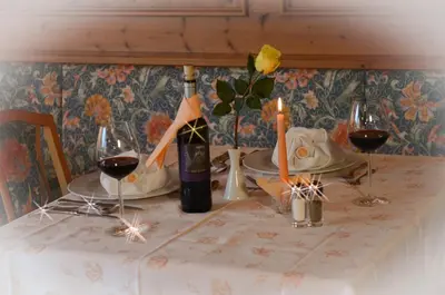 a table with a bottle of wine and two glasses of red wine at Pension Felseneck in San Leonardo in Passiria