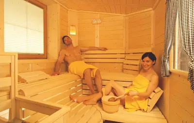 a man and a woman sitting in a sauna at Pension Felseneck in San Leonardo in Passiria