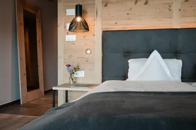 a table with a drink and a book on a couch at Hotel Alpenrose in Schenna