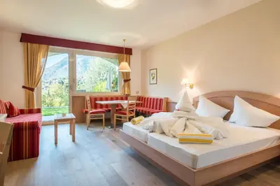 a bedroom with a bed and a table and chairs at Hotel Wessobrunn in Merano