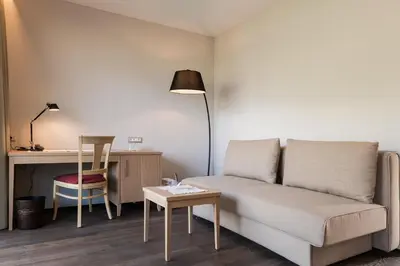 a living room with a couch and a desk at Hotel Wessobrunn in Merano