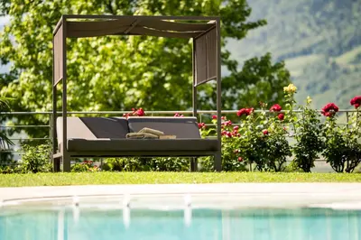 a bed with an umbrella next to a swimming pool at Hotel Wessobrunn in Merano