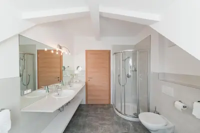 a bathroom with two sinks and a shower and a toilet at Hotel Wessobrunn in Merano