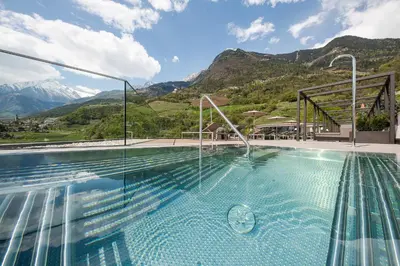 a swimming pool with mountains in the background at Hotel Wessobrunn in Merano