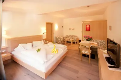 a hotel room with a bed and a dining room at Hotel Wessobrunn in Merano