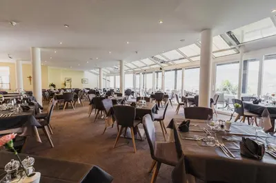 a dining room with tables and chairs and windows at Hotel Wessobrunn in Merano