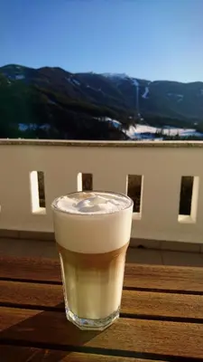 a glass of coffee sitting on a wooden table at Residence Sonnberg in Perca