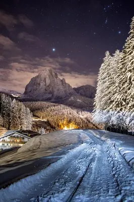 a snowy road at night with a mountain in the background at Hotel Jägerheim 3S in Selva di Val Gardena