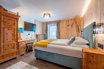 a bedroom with a large bed and a desk at Hotel Jägerheim 3S in Selva di Val Gardena