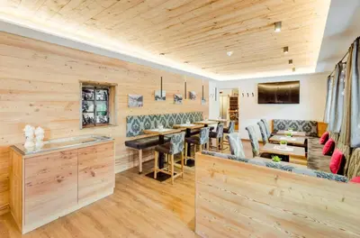 a restaurant with wooden walls and tables and chairs at Hotel Jägerheim 3S in Selva di Val Gardena