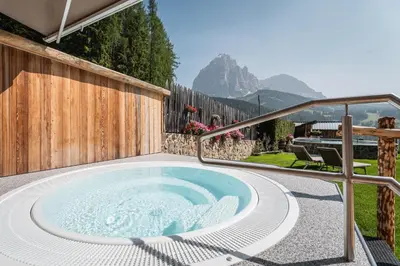 a hot tub on the patio of a house at Hotel Jägerheim 3S in Selva di Val Gardena