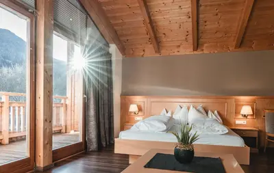 a bedroom with a bed and a large window at Hotel Reischach in Brunico
