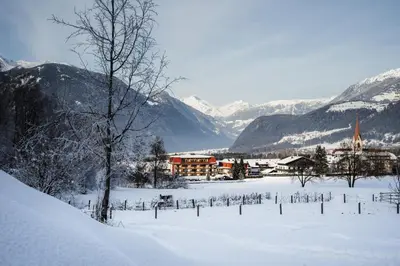 a village in the snow with mountains in the background at Hotel Reischach in Brunico