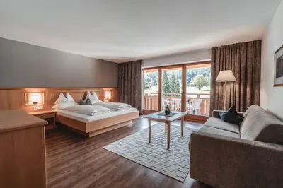 a hotel room with a bed and a couch at Hotel Reischach in Brunico