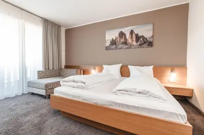 a hotel room with a bed and a chair at Hotel Reischach in Brunico