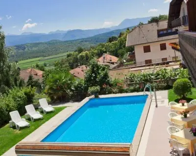 a swimming pool with chairs and a house at Pension Steingarten in Appiano sulla Strada del Vino