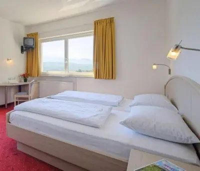 a bedroom with a large white bed with a window at Pension Steingarten in Appiano sulla Strada del Vino