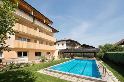 a swimming pool in a yard next to a building at Pensione Penegalblick in Appiano sulla Strada del Vino