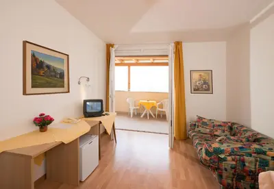a living room with a couch and a desk with a television at Pensione Penegalblick in Appiano sulla Strada del Vino