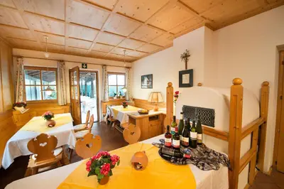 a living room with two tables and wine bottles at Pensione Penegalblick in Appiano sulla Strada del Vino