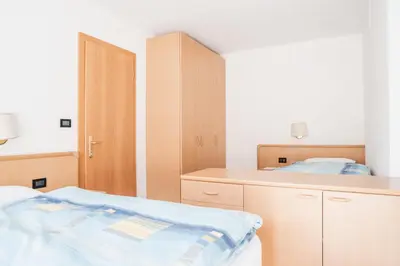 a bedroom with a bed and a desk and cabinets at Residence Dolomia in Pozza di Fassa