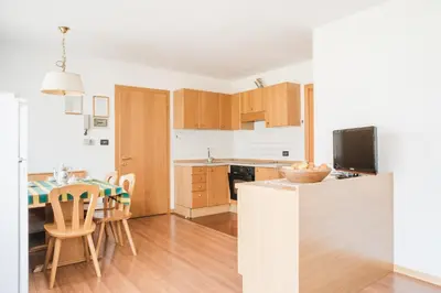 a kitchen and dining room with a table and chairs at Residence Dolomia in Pozza di Fassa