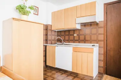 a kitchen with wooden cabinets and a sink at Residence Dolomia in Pozza di Fassa