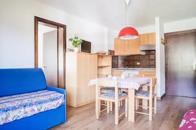 a small kitchen with a table and a blue couch at Residence Dolomia in Pozza di Fassa