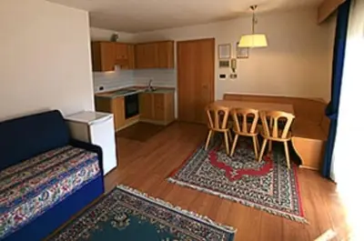 a living room with a kitchen and a table and chairs at Residence Dolomia in Pozza di Fassa