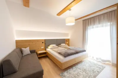 a bedroom with a bed and a couch at Ferienwohnungen Lanserhof in Appiano sulla Strada del Vino