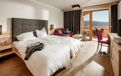 a bedroom with a white bed and a table at Panoramahotel Huberhof in Maranza