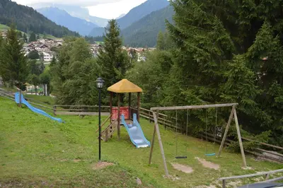 a playground in a field with a slide at Hotel Val Di Fassa in Soraga