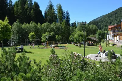 a park with people playing in the grass at Hotel Val Di Fassa in Soraga