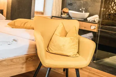 a chair with a pillow on it next to a bed at Ansitz Zehentner in Laion