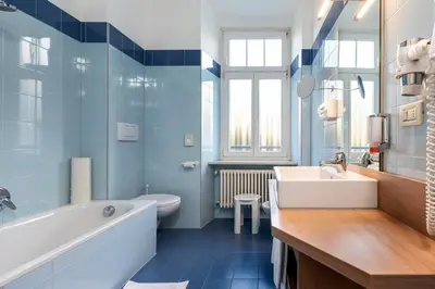 a blue bathroom with a tub and a sink at Hotel Kolping in Merano
