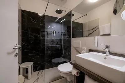 a bathroom with a sink and a toilet and a shower at Hotel Kolping in Merano