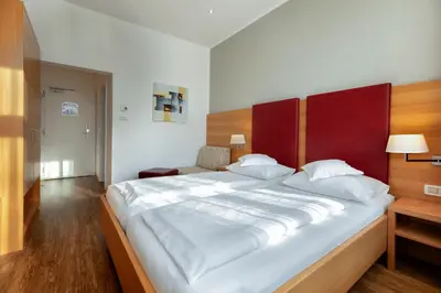 a bedroom with a large white bed with a red headboard at Hotel Kolping in Merano