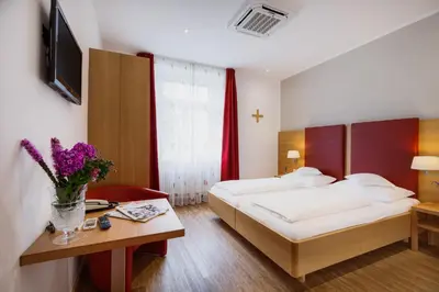 a hotel room with a bed and a table with flowers at Hotel Kolping in Merano