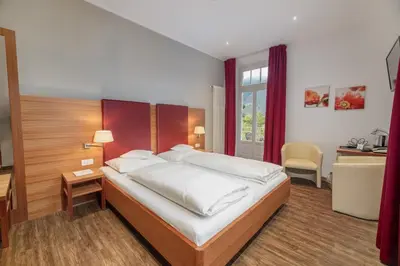 a bedroom with a large bed with a desk and a desk at Hotel Kolping in Merano
