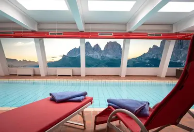 a swimming pool with a red bench in front of a pool at Hotel Garni Gonzaga in Canazei
