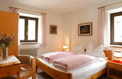 a bedroom with two beds and a table and windows at Hotel Garni Gonzaga in Canazei