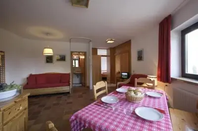 a living room with a table with a red and white table cloth at Hotel Garni Gonzaga in Canazei