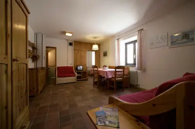 a living room with a table and a dining room at Hotel Garni Gonzaga in Canazei