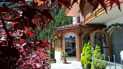 a garden entrance to a house with red plants at B&B Hotel Alpenrose Rooms & Apartments in Valles