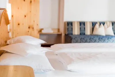 two beds with white pillows in a room at B&B Hotel Alpenrose Rooms & Apartments in Valles
