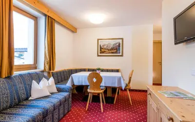 a hotel room with a table and a couch at B&B Hotel Alpenrose Rooms & Apartments in Valles