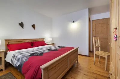 a bedroom with a large bed with red pillows at Maso Vaia in Cavalese