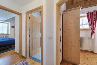a room with an open door and a bedroom at Maso Vaia in Cavalese