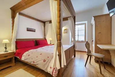 a bedroom with a canopy bed with red pillows at Maso Vaia in Cavalese