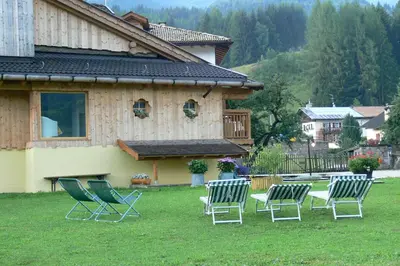 a group of chairs sitting in the grass in front of a house at Maso Vaia in Cavalese